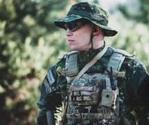 Airsoft military game player in camouflage uniform with armed assault rifle