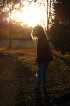 a woman standing in a park at sunset