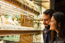 young couple choosing wedding rings while smiling while doing shopping in Florence