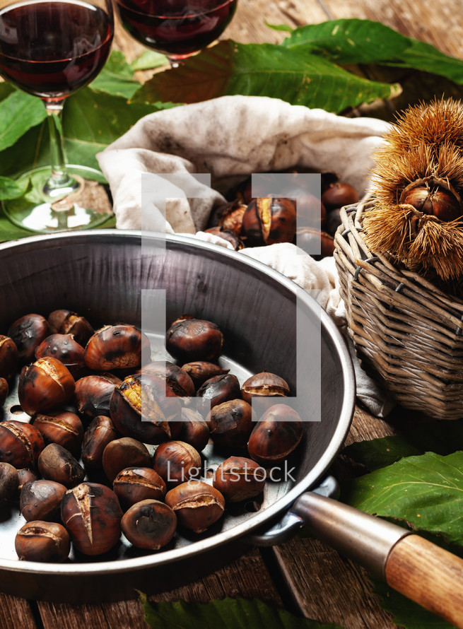 Roasted chestnuts in iron skillet on wooden table