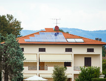 Photovoltaic solar panel on a roof. In background gray cloudy sky.