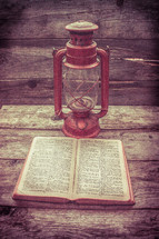 lantern and open Bible on wood boards 