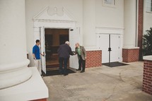 greeters welcoming parishioners at church doors 