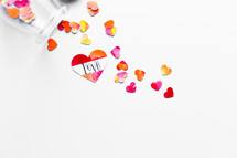 Top view of watercolor hearts scattered on white background with one labeled LOVE. 