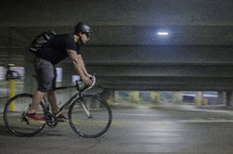 a man riding a bicycle in a parking garage 