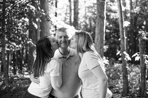 daughters kissing dad on the cheeks 