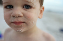 Close up of little boy with sand all over his face