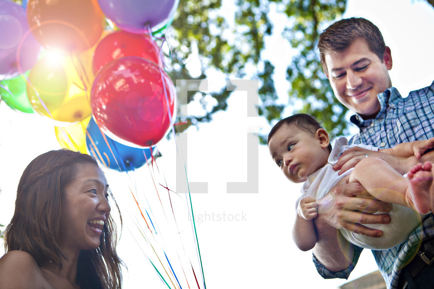 mother holding balloon and father holding a baby