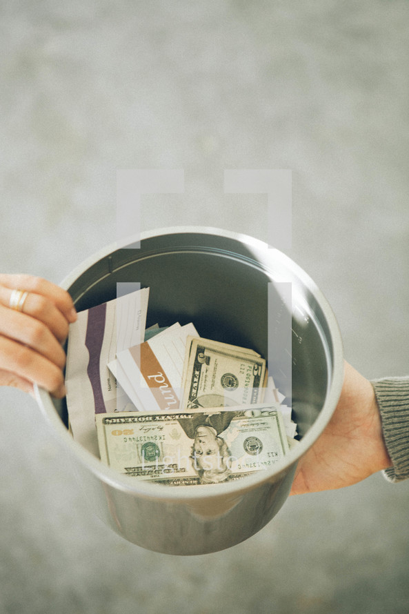 Offering bucket being passed with money and checks inside