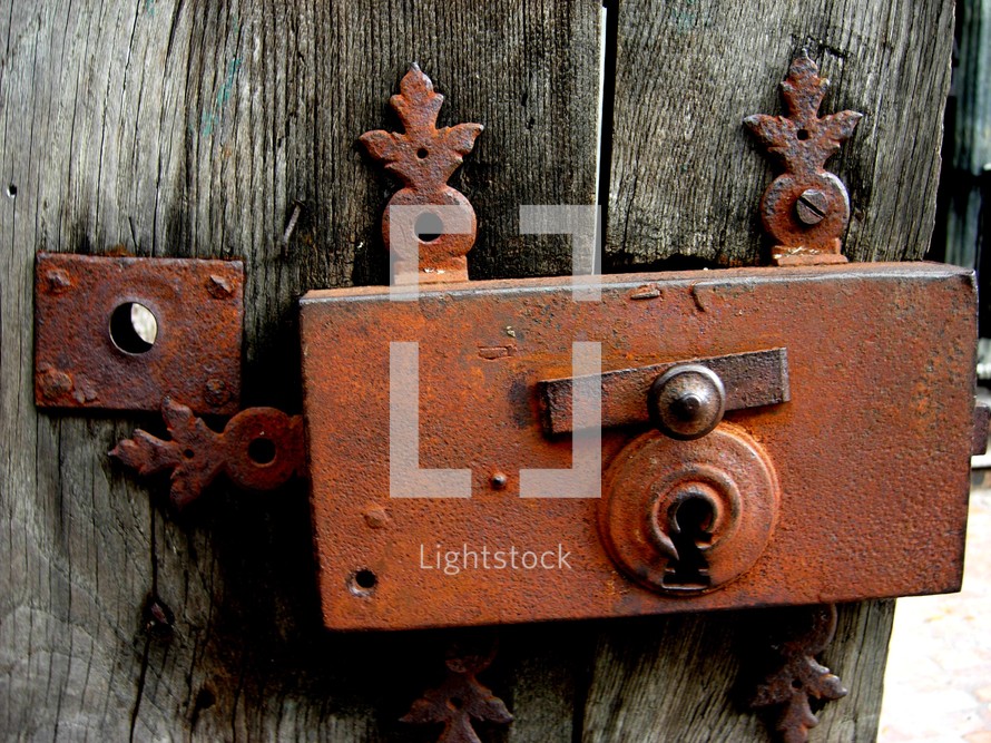 Lock and key of an old gated door that is rusty and weather beaten and worn by time, climate and weather. 
