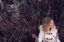 A woman in a white coat stands in tall grass.