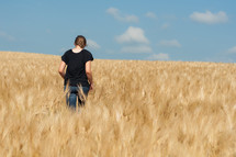 woman walking through a field of wheat 