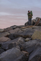 father and son on rocks on a beach 