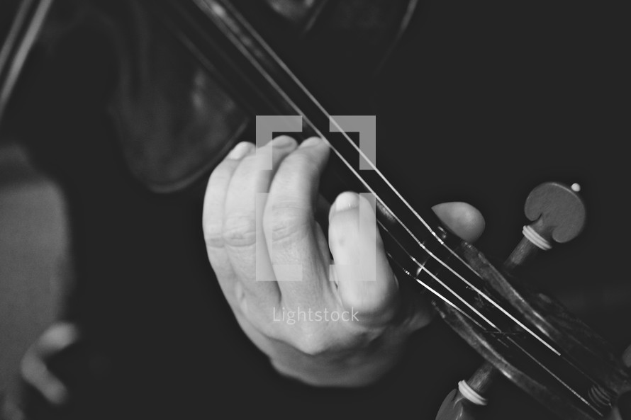 Hand holding neck of violin.