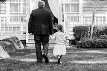 a father walking holding his daughter's hand 
