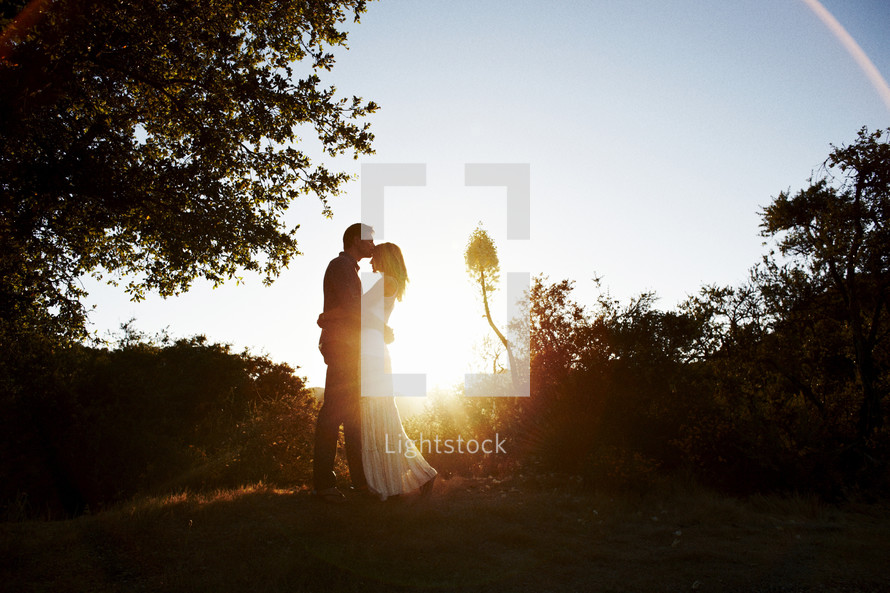 couple kissing outdoors under the glow of sunlight