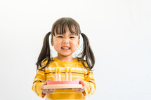 child holding a toy birthday cake 