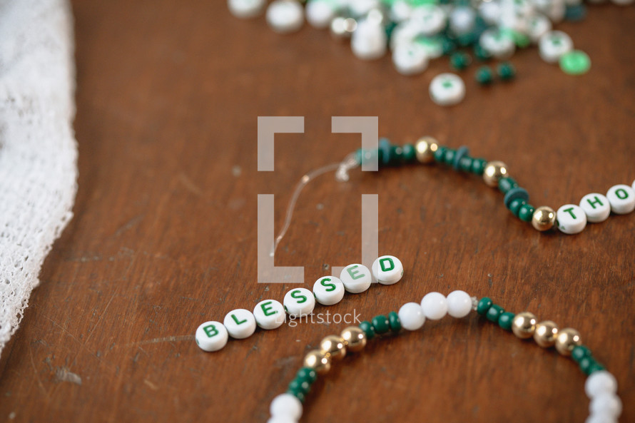 Jar of green, white, and gold beads with word - blessed