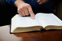 elderly man with his finger pointing to scripture 