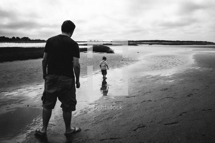 father and son walking down a beach 