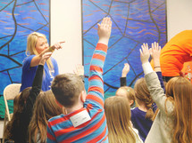 a teacher and students raising their hands 