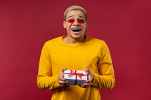 Stylish man with gift box on red background