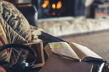 open Bible, headphones, tablet, and journal on a coach in front of a fire place