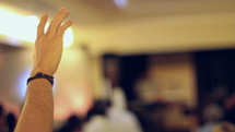man with hands raised at a worship service