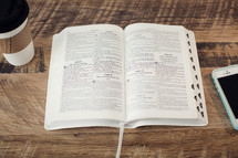 coffee cup, open Bible, and cellphone on a desk 