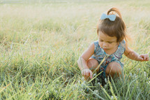 toddler girl playing in a field 