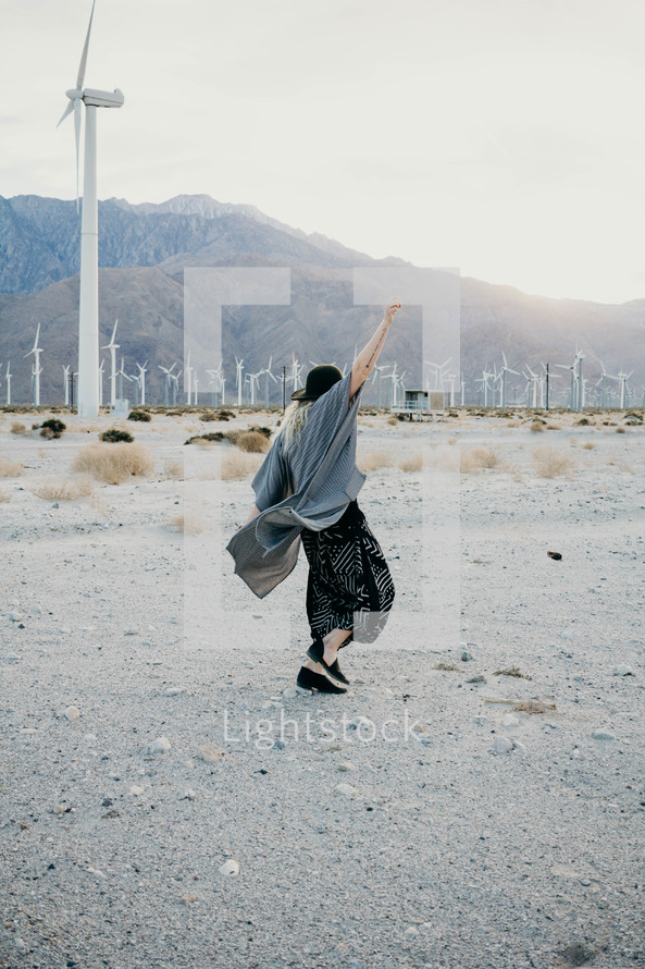a woman standing in a desert and view of wind turbines 