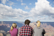 friends sitting at the edge of a canyon cliff 