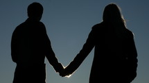 Silhouette of couple holding hands in the moonlight.
