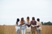 a group of young women standing in a field 