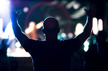 man at a worship service with hands raised 