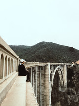 a man sitting at the edge of a bridge 