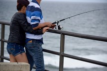 a couple snuggle and fishing on a pier 