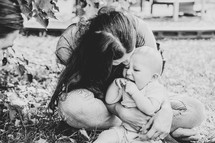 Woman kissing laughing baby in black and white