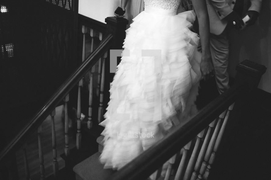 torso of a bride and groom walking down stairs