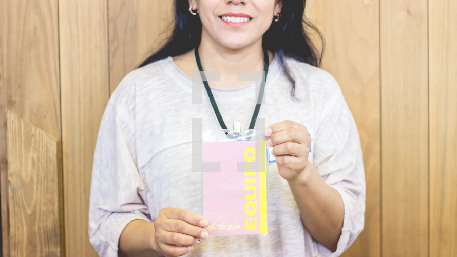 a woman holding up a badge pass 