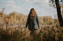a woman walking in a field in fall 