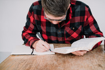 man writing in a journal and reading a Bible 