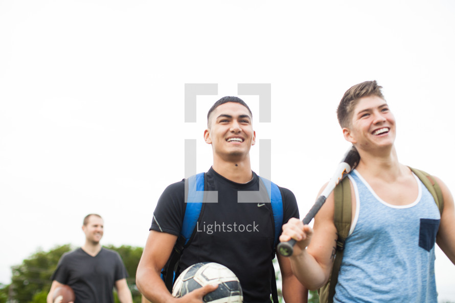 athletes standing on a sports field carrying sports equipment 