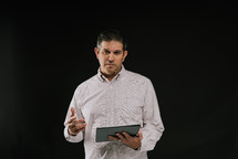 a man holding a tablet speaking 