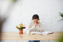 woman sitting at a desk with a Bible praying 