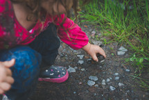 a girl picking up rocks in the dirt 