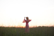a woman in a pink dress walking through a field 