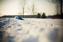 child lying on a sled in the snow