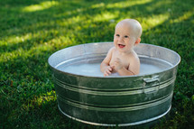 baby in a metal tub outdoors 