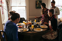 a table setting for breakfast and women gathered around the table 